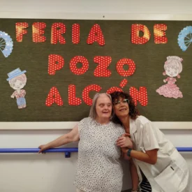 Residente y trabajadora de la residencia Escoriza posando frente al decorado realizado por los residentes por las fiestas en honor a Santa Ana de Pozo Alcón