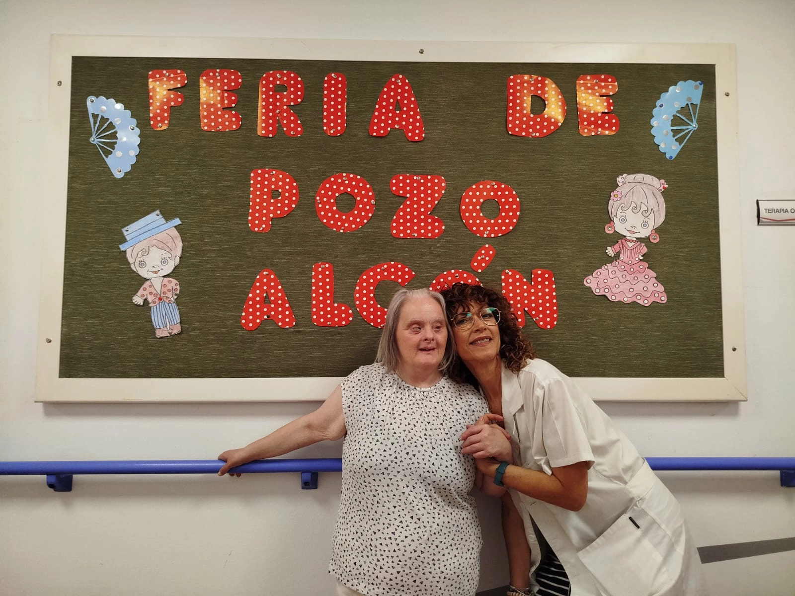 Residente y trabajadora de la residencia Escoriza posando frente al decorado realizado por los residentes por las fiestas en honor a Santa Ana de Pozo Alcón